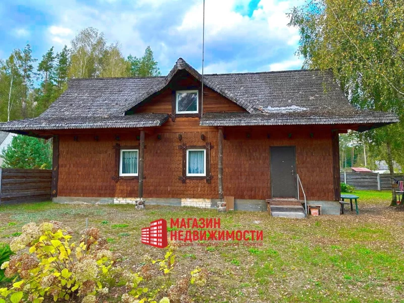 Хутар у вёсцы Загорнікі пад Гроднам. Драўляны дом з саламяным дахам, акружаны дрэвамі і травяністым дваром.